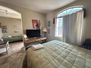 a bedroom with a bed and a desk with a television at Casa Villafontana in Mexicali