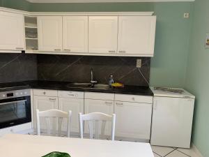 a kitchen with white cabinets and a sink and chairs at Ferienwohnung Sprjewja in Straupitz