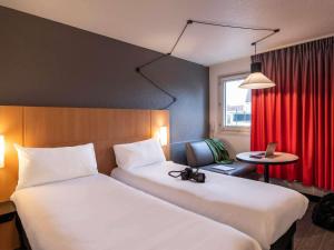 a hotel room with two beds and a red curtain at ibis Cergy Pontoise Le Port in Cergy +76 photos