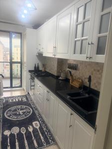 a kitchen with white cabinets and a black counter top at Modern Flat Near Bucharest in residence in Dobroeşti