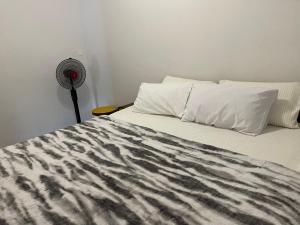 a bed with a black and white comforter and a fan at Kokoma Apartment in Katima Mulilo in Katima Mulilo