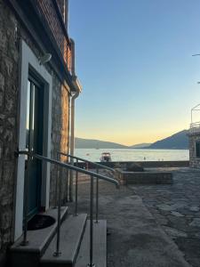 a building with a door and a railing next to the water at Apartments Klara in Donja Lastva