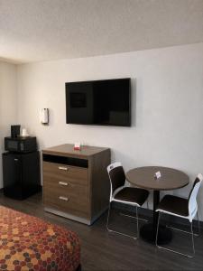 a hotel room with a table and a flat screen tv at Econo Lodge Calhoun South in Calhoun
