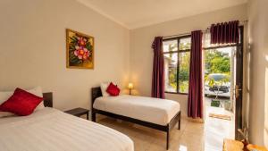 a bedroom with two beds and a window with a view at Cahaya Adrian Hotel in Labuan Bajo