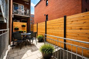 a patio with a table and chairs and a fence at Jolie Condo Great Location 2BD presented by TripMontreal I in Montreal