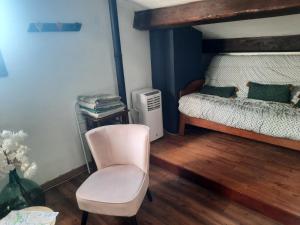 a bedroom with a white chair and a bed at 2 chambres lit140 et 2lits 90 dans villa piscine extérieure 24h sur 24 h cadre champêtre in Lapeyrouse-Fossat