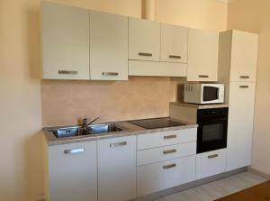 a kitchen with white cabinets and a sink and a microwave at Ca' Sonenga in Menaggio