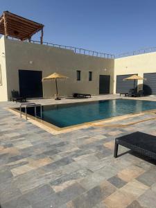a swimming pool with benches and umbrellas in a building at Villa neuve pour un séjour agréable à Essaouira in Essaouira
