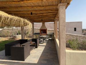 a patio with a table and chairs under a wooden roof at Villa neuve pour un séjour agréable à Essaouira in Essaouira