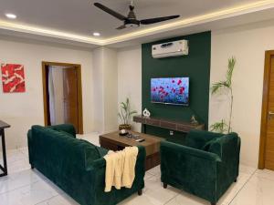 a living room with two green chairs and a flat screen tv at Executive 2 bedrooms in Rawalpindi - Self Checkin in Rawalpindi