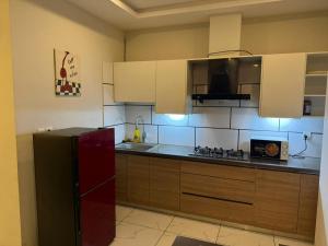 a kitchen with a black refrigerator and white cabinets at Executive 2 bedrooms in Rawalpindi - Self Checkin in Rawalpindi