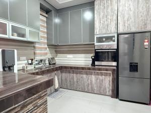 a kitchen with stainless steel appliances and wooden cabinets at Teratak Chena - Lux Bungalow in Kuala Terengganu