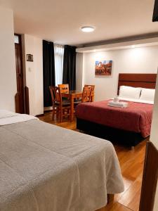 a hotel room with two beds and a table and chairs at Artezana Hotel in Cusco