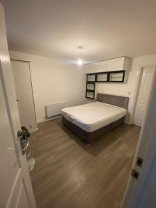 a bedroom with a bed and a wooden floor at MK WhiteHouse cottage in Milton Keynes