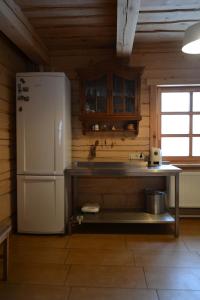 eine Küche mit einem weißen Kühlschrank und einem Tisch in der Unterkunft Sodyba Širvynė in Užpaliai