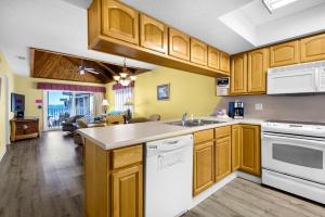 a kitchen with wooden cabinets and white appliances at Soundside Holiday Beach Resort in Pensacola Beach