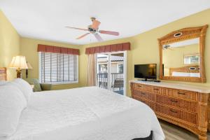 a bedroom with a white bed and a mirror at Soundside Holiday Beach Resort in Pensacola Beach +87 photos