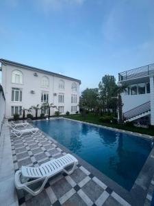 a swimming pool with two lounge chairs next to a building at Gabala Palm Villa in Gabala