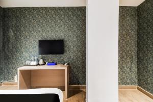 a room with a tv on a wall with a table at Hotel O Sivalika Inn in Kolkata +24 photos