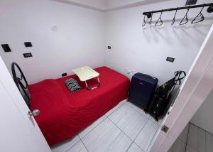 a small room with a red bed and luggage at Studio Brasil 861 in Lima