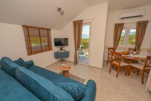 a living room with a blue couch and a table at Green Oasis Residence in Radanovići