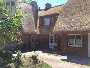 an old brick house with a thatched roof at Ferienwohnung Roman in Tinnum