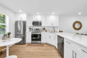 a kitchen with white cabinets and stainless steel appliances at The Beach Villa in Juno! 1-Steps to the Beach in Juno Beach