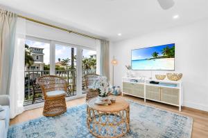a living room with a tv and wicker chairs at ON The Beach Juno! 3-Top Rated Villa! in Juno Beach