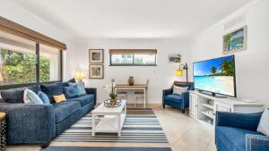 a living room with a blue couch and a tv at ON The Beach Juno! Modern Lux Seaside! in Juno Beach