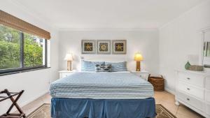 a white bedroom with a bed and two windows at ON The Beach Juno! Modern Lux Seaside! in Juno Beach