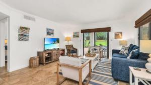 a living room with a blue couch and a tv at Juno Beach Seaside Escape I Steps from the Ocean! in Juno Beach