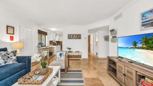a living room with a blue couch and a large screen tv at Juno Beach Seaside Escape I Steps from the Ocean! in Juno Beach