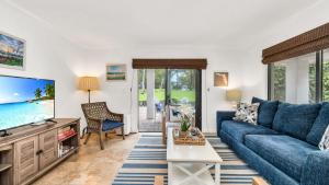 a living room with a blue couch and a tv at Juno Beach Seaside Escape I Steps from the Ocean! in Juno Beach