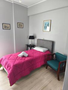 a bedroom with a pink bed and a blue chair at Nicolas Luxury Apartment in Amalias