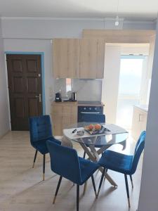 a kitchen with a table and blue chairs in a room at Nicolas Luxury Apartment in Amalias