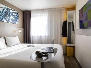 a hotel room with a bed with a laptop on a table at ibis Styles Paris Bercy in Paris