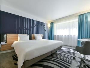 a bedroom with a large bed and a blue wall at Novotel La Rochelle Centre in La Rochelle