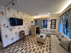 a living room with a couch and a tv on the wall at The AISHANA PAHALGAM in Pahalgām