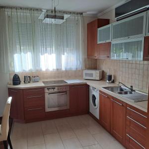 a kitchen with wooden cabinets and a sink and a microwave at Citadella apartman in Pusztavacs