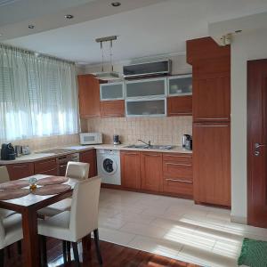a kitchen with wooden cabinets and a table with chairs at Citadella apartman in Pusztavacs