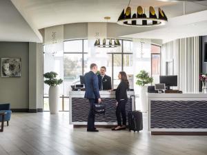 a group of people standing at a counter in an office at Novotel Ipswich Centre in Ipswich