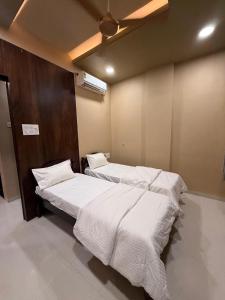 a bedroom with two beds and a ceiling fan at Ramona homestay in Kolhapur