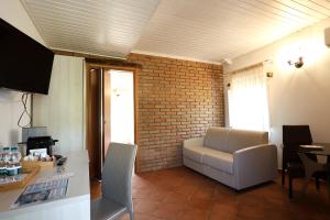 a living room with a white chair and a brick wall at VILLA MARIA ELENA Charme Rooms sul mare in Capo Vaticano