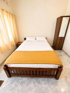 a bedroom with a bed with a yellow blanket on it at Sree Madhavam Stays AC Family Homestay Near Padmanabhaswamy Temple in Trivandrum