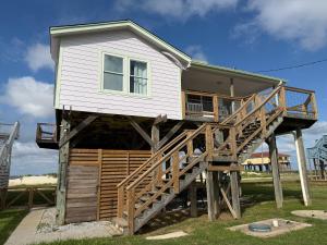 a house on logs with a balcony and stairs at The Pelican Pass in Freeport