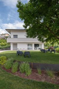 a white building with black benches in the grass at el Zhìgol B&B in Farra di Soligo