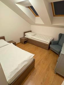 a bedroom with two beds and a blue chair at Apartmán JAMI REZIDENCIA in Spišské Podhradie