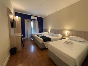 a hotel room with three beds and a window at Sense Hotel Araucária in Araucária