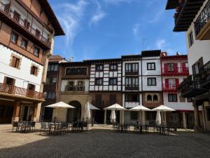 a courtyard with tables and umbrellas in front of a building at KAIOA .Incluye parking privado. in Hondarribia