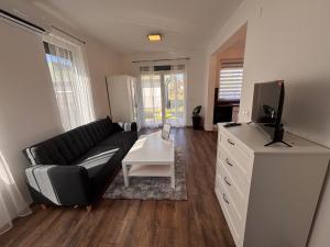 a living room with a black couch and a tv at Argent apartman in Balatonmáriafürdő